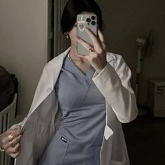 a woman taking a selfie with her cell phone in front of her face while wearing a lab coat