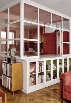 a living room filled with lots of furniture and bookshelves next to a red couch