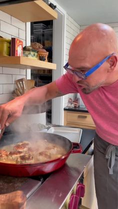 a man cooking food in a pan on top of a stove next to an oven