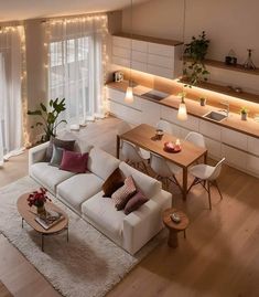 a living room filled with white furniture and lots of lights on the wall above it