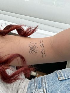 a woman with red hair has a tattoo on her arm and the word love is written in cursive writing