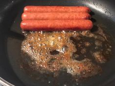 two hot dogs are cooking in a frying pan on the stove top with oil