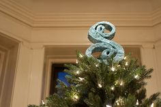 a decorated christmas tree in front of a window with lit candles and a snake on top