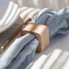 a napkin holder with a wooden handle on top of a white table cloth next to plates and utensils