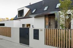 a white house with black doors and wooden slats on the front fence is seen in this street view