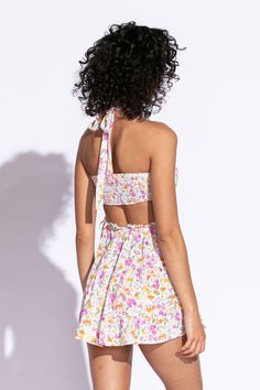 STYLE INFORMATION: Get your Texas boho vibes on in the Sundown Wildflower Floral Print Sundress!. Wildflower floral print, in hues of pink, orange, green, and yellow shapes this cute dress that has a halter V-neckline with tie straps, and a cutout waist.. The open back wraps around to the sides to create a cutout effect above the attached mini skirt. Ruffle trim and side ties decorate the cutout waist. DETAILS & CARE: Rayon/Polyester. Dry Clean. Imported. SHIPPING: We offer free shipping for all Spring Halter Mini Dress For Summer Parties, Spring V-neck Halter Dress With Crisscross Straps, Summer Dress With Spaghetti And Wrap-around Straps, Brunch Halter Dress With Tie Back, Summer Dresses With Spaghetti And Wrap-around Straps, Brunch Halter Neck Dress With Tie Back, Halter Neck Dress With Tie Back For Brunch, Strapless Summer Sundress With Tie Back, Vacation V-neck Halter Top With Tie Back