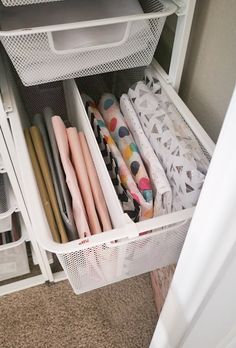 an organized closet with white bins filled with crafting supplies and storage containers on the bottom shelf