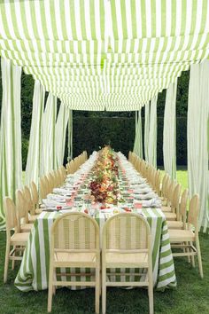 a long table is set with green and white striped linens for an outdoor party