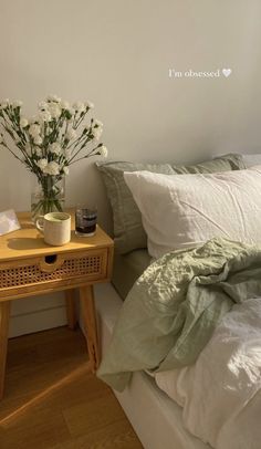 a small table with flowers on it next to a bed