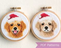 two cross stitch dogs with santa hats on their heads, one is brown and the other is white