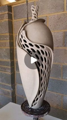 a white sculpture sitting on top of a table next to a brick wall