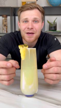 a man is holding up a drink in front of his face while posing for the camera