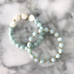 We are just smitten with this Bracelet! These beautiful mother of pearl hearts + mint colored gemstone beads are a subtle yet stunning combination! Pair it with it's matching Stackable or worn solo for a sweet look! Details:- Gorgeous Natural Green Angelite Beading - Mother of Pearl Hearts- Gold Accents- Stretches to fit most wrists approximately 6.5-7" in length Free U.S. Shipping on orders over $75!Your jewels will arrive in one of our velvet gift pouches. Perfect for gifting, storing your del Elegant Amazonite Beaded Bracelets, White Beaded Amazonite Jewelry, White Amazonite Bracelets With Natural Stones, White Amazonite Bracelet With Natural Stones, Mint Bracelet, Mother Of Pearl Bracelet, Beads Bracelet Design, Bracelet Design, Beads Bracelet