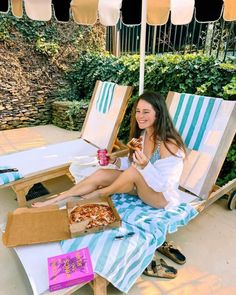 a woman sitting on a beach chair eating pizza