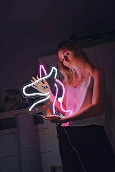 a woman holding a lit up unicorn in her hands