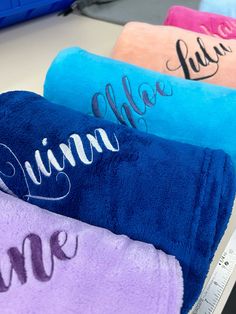 three personalized towels are sitting on a table with a measuring tape in front of them