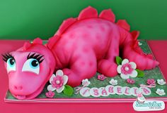 a pink dragon cake with flowers on it