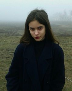 a woman standing in a field with fog