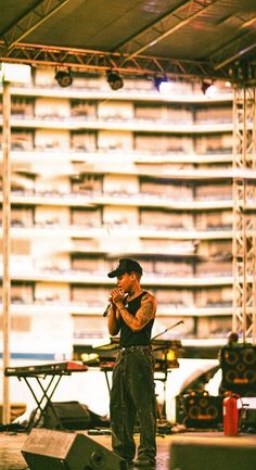 a man standing on top of a stage next to a guitar case and amps