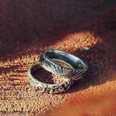 two silver rings sitting on top of a sandy ground next to each other in the sun