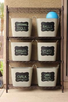 four white buckets with chalkboard labels on them sitting in front of a building