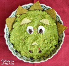 a bowl filled with guacamole and chips on top of a red cloth