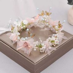 a close up of a tiara on a box with flowers and butterflies around it