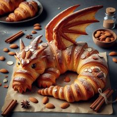 a pastry shaped like a dragon sitting on top of a table next to nuts and cinnamons