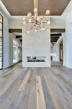 a large white room with wooden floors and a chandelier hanging from the ceiling