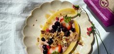 a white plate topped with fruit and granola next to a box of yogurt