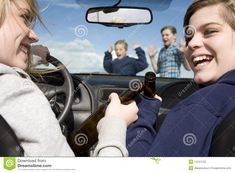 two women sitting in the driver's seat of a car and one is holding a beer