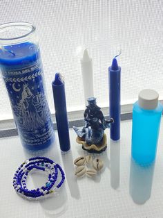 candles, beads and bracelets are sitting on a table next to a glass bottle