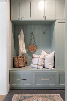 a bench with some pillows on top of it next to a rug and coat rack