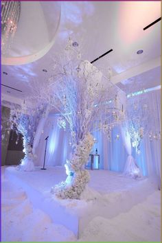 a white wedding setup with chandeliers and flowers on the tree in the center