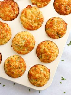 an overhead view of some muffins on a white tray with green sprigs