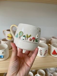 a person holding up a coffee cup with designs on it