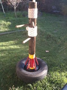 a tree made out of old tires in the grass with rope wrapped around it's branches