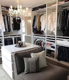 an organized closet with clothes and chandelier