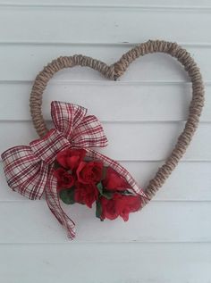 a heart shaped wreath with red roses tied to it