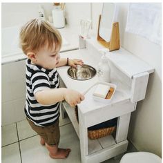 a little boy that is standing in front of a sink with a bowl on it