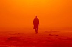 a man standing on top of a sandy beach under a yellow sky in the sun