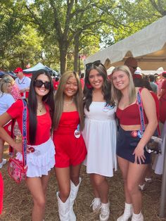 three girls in red and white outfits posing for the camera at an outdoor event with other people