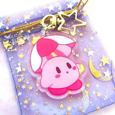 a pink pig keychain hanging from a chain on top of a purple bag