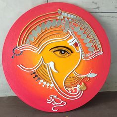 an elephant head painted on the side of a red frisbee with gold accents