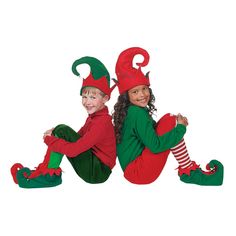 two children dressed in elf costumes sitting on the ground with their legs crossed and smiling