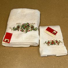 two white towels are sitting on the floor next to each other with red trimmings