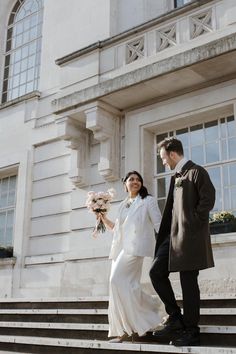 a bride and groom walking up the steps to their wedding ceremony in front of an old building