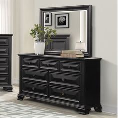 a black dresser with a mirror on top of it and a plant in the middle