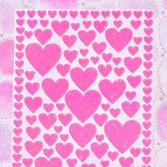 pink glitter hearts stickers on white paper in the shape of a square, heart