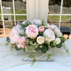 a bouquet of pink and white flowers sitting on top of a table next to a window